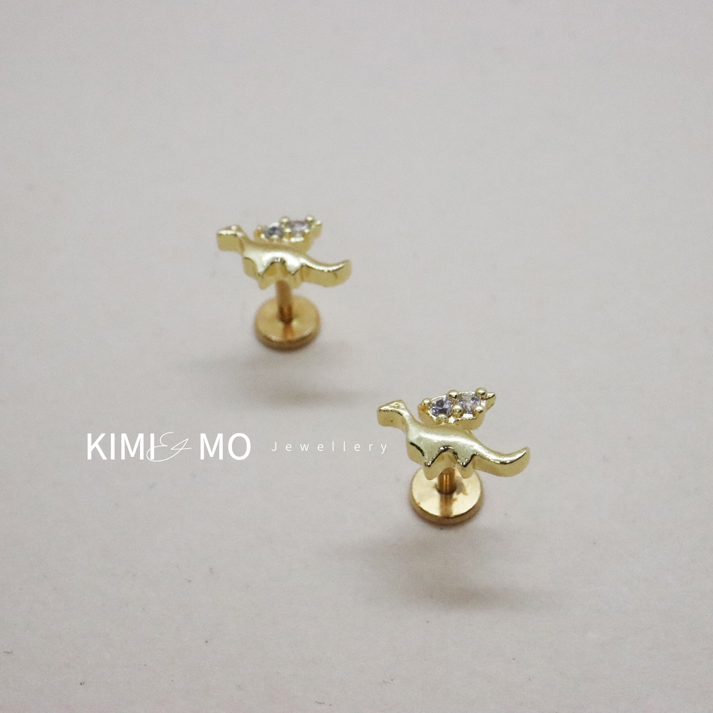 Gold dinosaur stud earrings with winged design and gemstone details