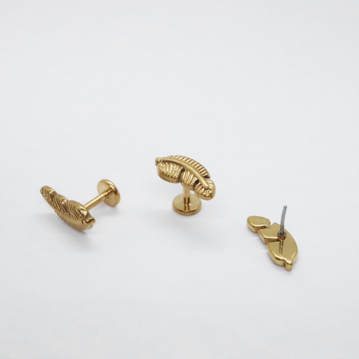 Gold-plated feather-shaped stud earrings on white background