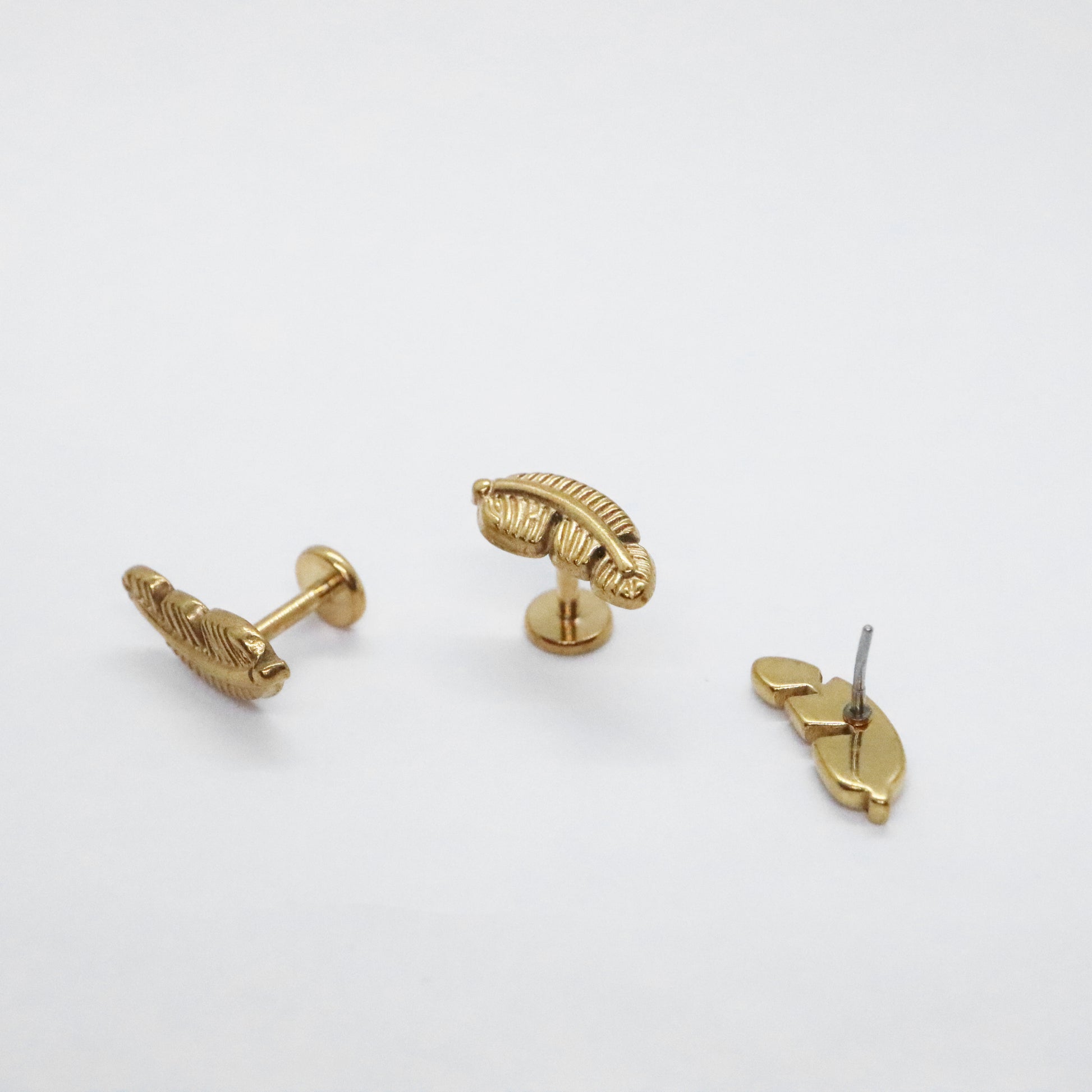 Gold-plated feather-shaped stud earrings on white background