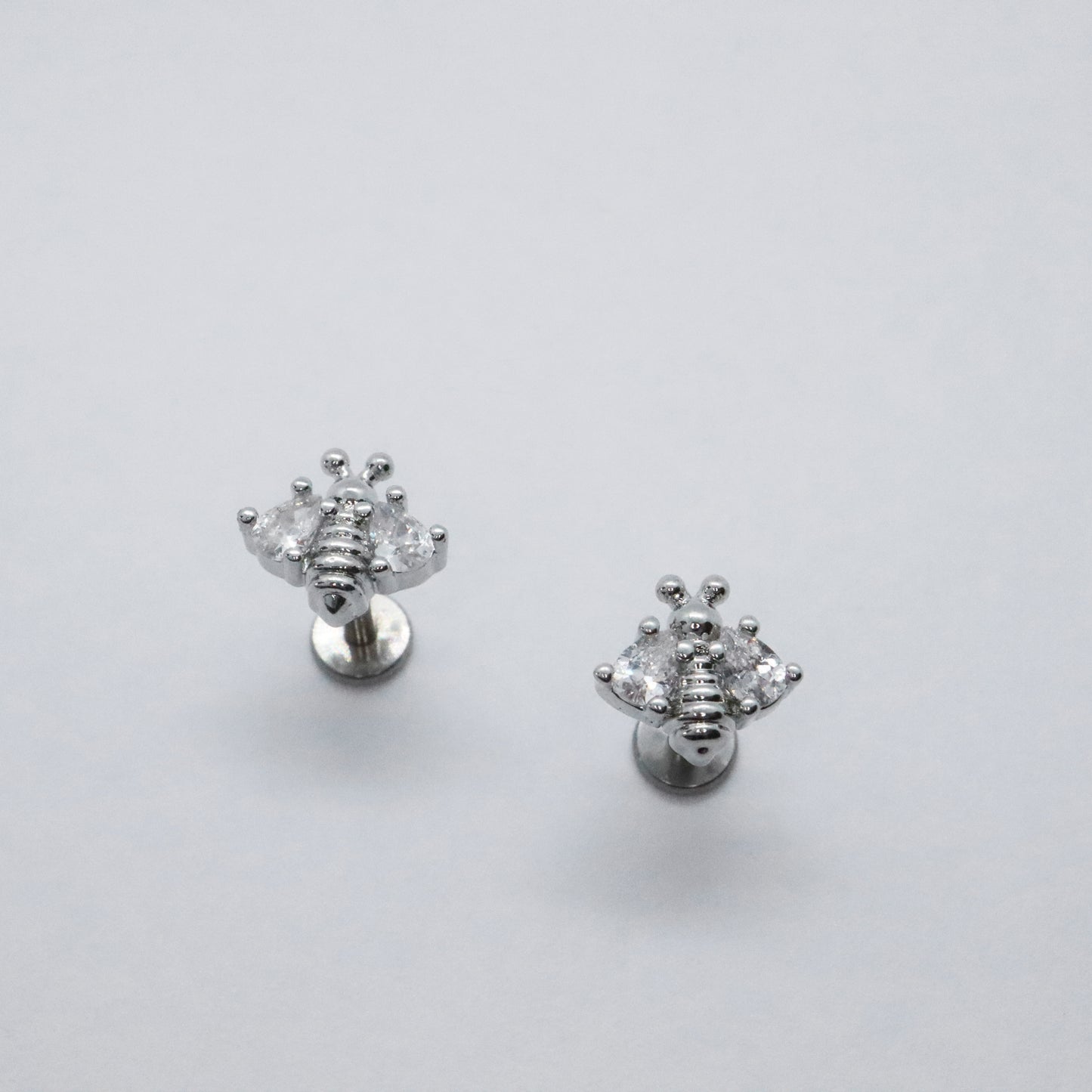 Trendy silver bee stud earrings with a modern flat back design